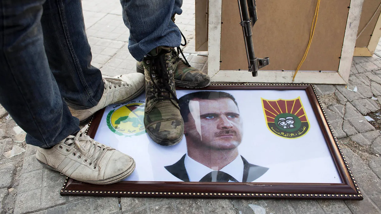 Der Widerstand gegen Assad wächst: syrische Widerstandskämpfer stehen in Aleppo auf einem Bild des Präsidenten