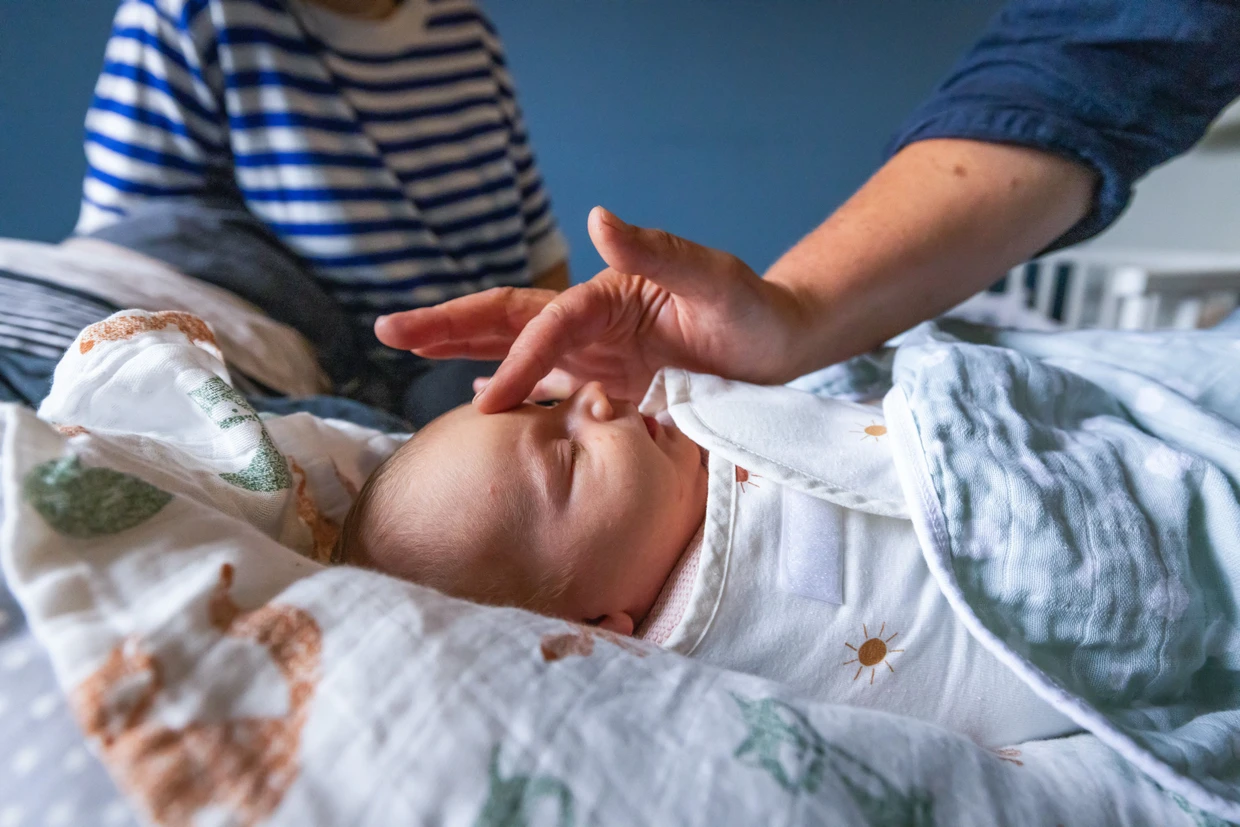 Una partera acaricia el rostro de un recién nacido.