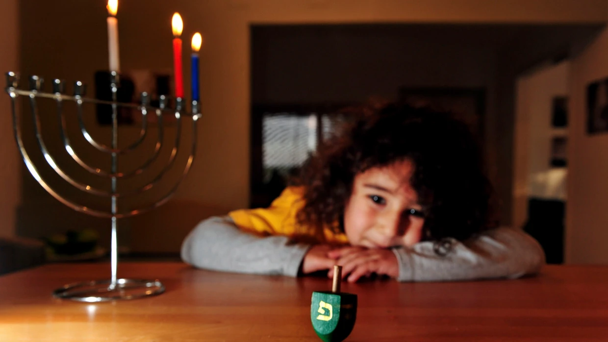 Ein jüdisches Kind spielt an Chanukka mit einem Dreidel