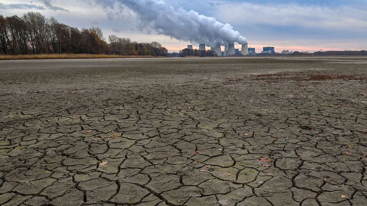 Risse auf dem Grund eines abgelassenen Karpfenteiches vor dem Hintergrund des Braunkohlekraftwerks Jänschwalde der Lausitz Energie Bergbau AG (LEAG)