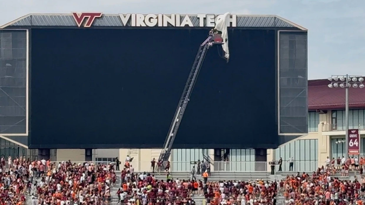 Retter sichern einen Fallschirmspringer, der vor dem NCAA-College-Footballspiel von Virginia Tech in die Anzeigetafel des Lane Stadium geprallt ist.