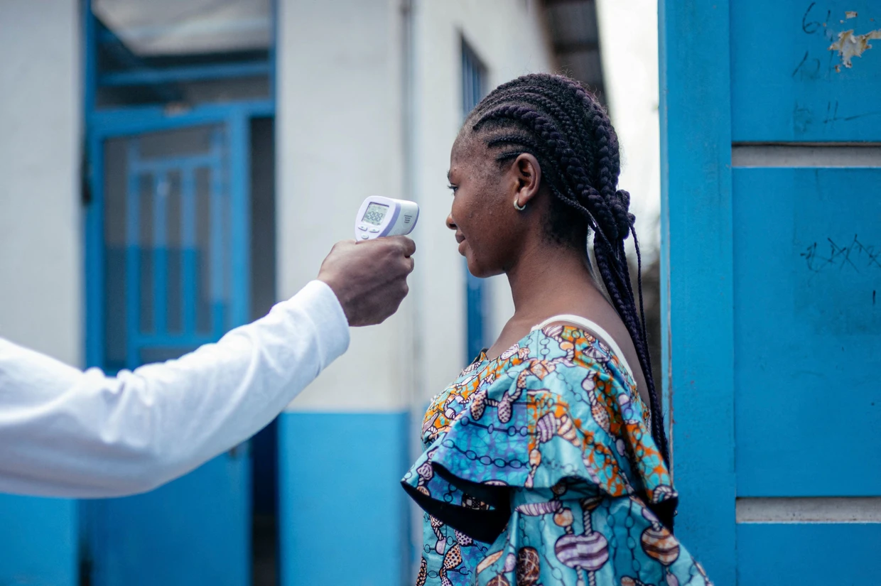 Ein Mitarbeiter des CBCA Virunga-Krankenhauses in Gome misst am 17. Mai die Temperatur einer Besucherin mit einem berührungslosen Infrarot-Thermometer, bevor er ihr den Zutritt zum Krankenhaus gewährt.