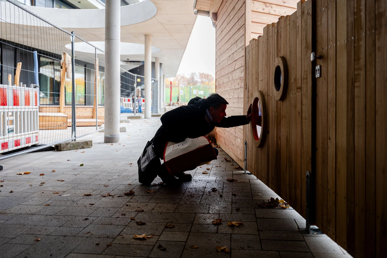 Inspektion: Markus Rathschlag schaut durch ein Sichtfenster des Spielplatzes.