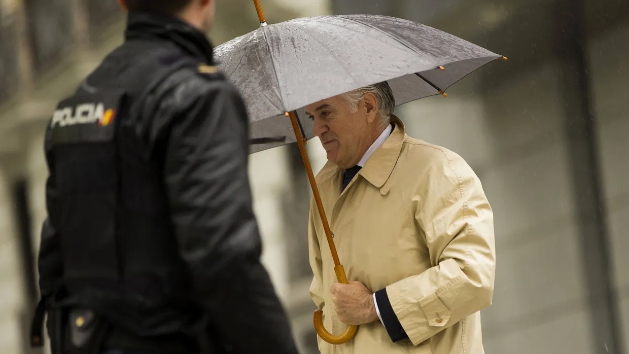 Der frühere PP-Schatzmeister Luis Bárcenas versteckt sich am Montag in Madrid unter einem Regenschirm.