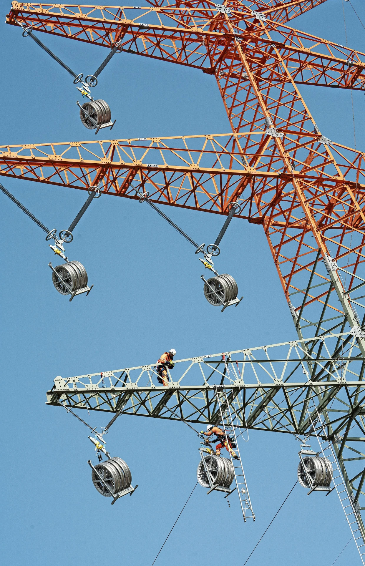Teamwork: Ein Monteur behält auf der Traverse den Helikopter im Blick, der Kollege legt das Seil ein.