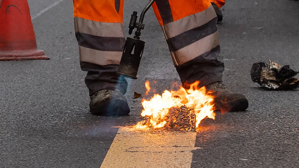 Ein Arbeiter entfernt die provisorischen Fahrbahnmarkierungen auf der Straße Unter den Linden in Berlin.