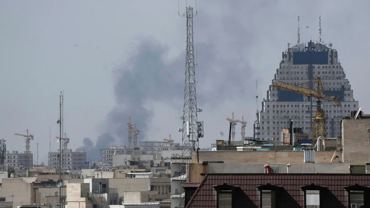 28.02.2026, Iran, Teheran: Rauch steigt nach einer Explosion im Hintergrund von Häusern auf.