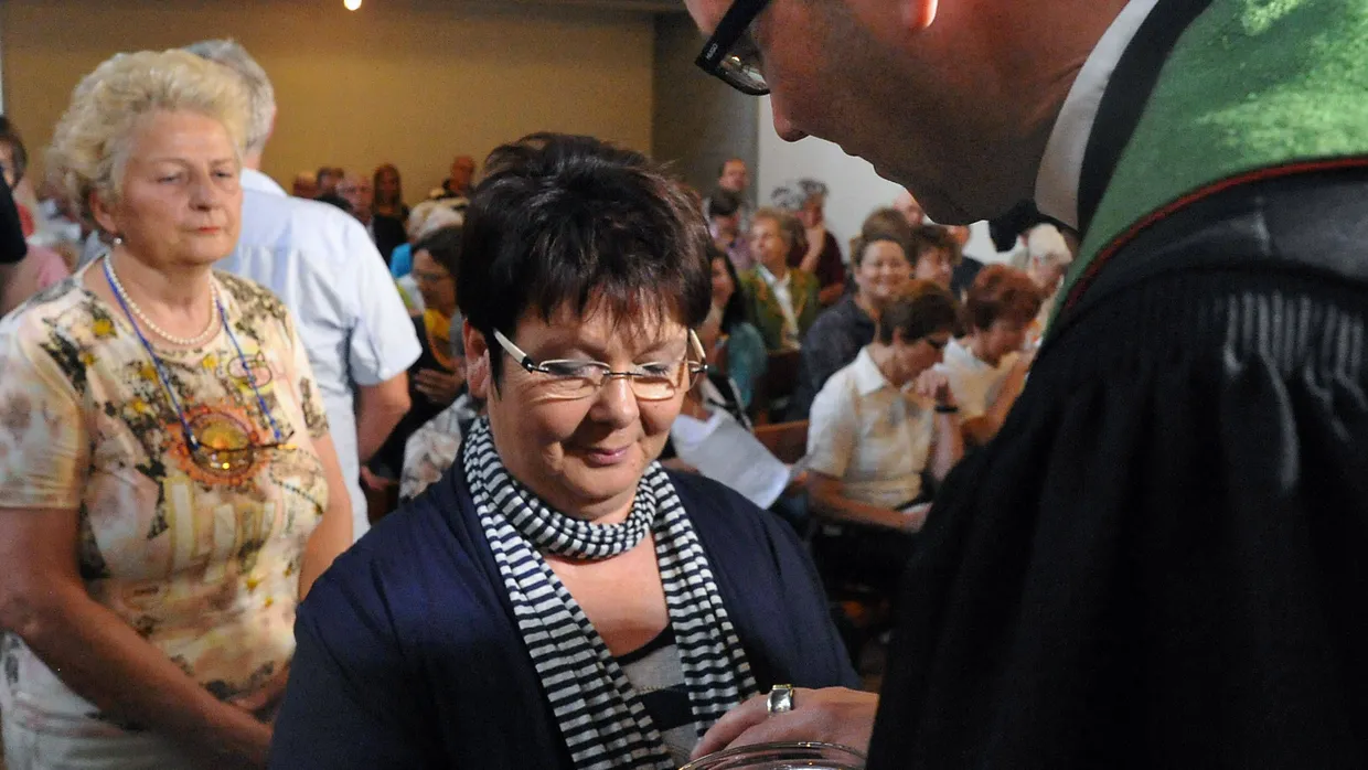 Pfarrer Ralf Schmidt salbt die Hände einer Gottesdienstbesucherin mit Öl.