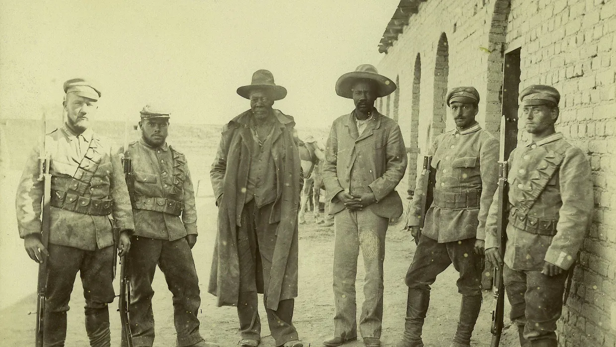 1896 in Okahandja, damals Kolonie „Deutsch-Südwestafrika“: Soldaten der deutschen Schutztruppe posieren mit ihren Gefangenen, den Stammesführern Kahimemua zusammen Nguvauva (3. von links) und Nikodemus Kavikunua. Beide wurden kurz danach hingerichtet.