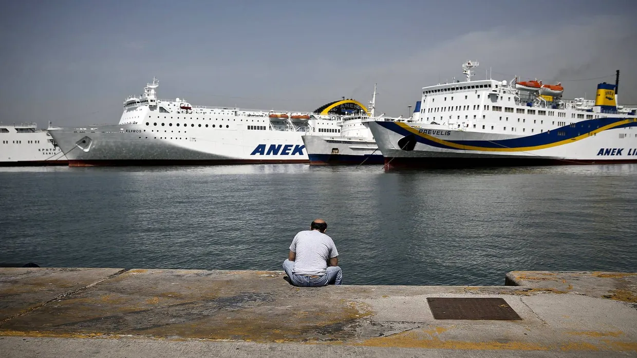 Ein Mann sitzt am Hafen von Piräus
