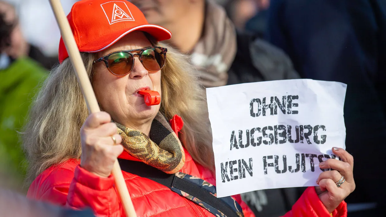 Teilnehmer einer Kundgebung der IG Metall gegen die Schließung des Fujitsu-Werkes Augsburg stehen auf dem Willy-Brandt-Platz an der Messe.