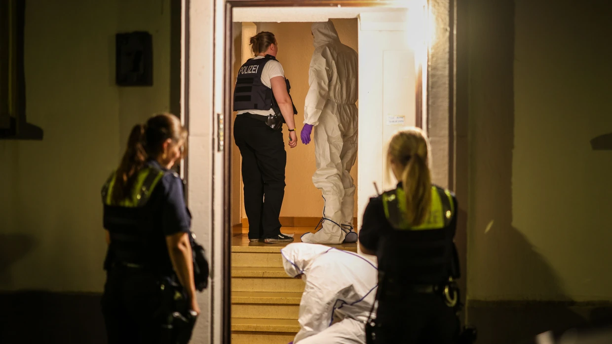 Beamte der Spurensicherung und Polizeibeamte stehen nach dem tödlichen Vorfall im Treppenhaus eines Mehrfamilienhauses in Krefeld.