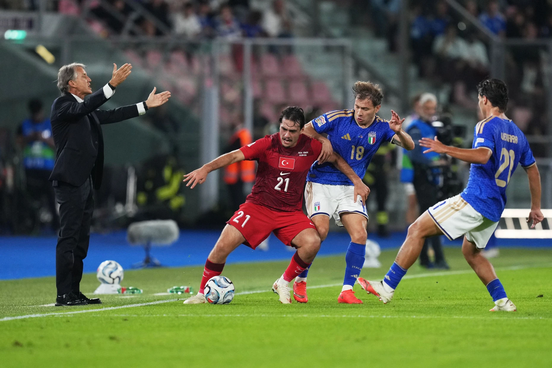 Der italienische Nationaltrainer Roberto Mancini gestikuliert, während der Türke Aral Simsir mit dem Italiener Nicolo Barella und Antonio Vergara um den Ball kämpft.