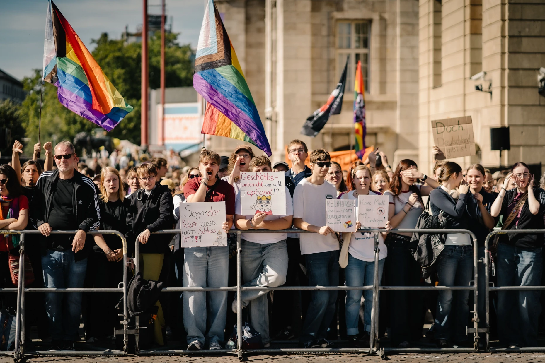 Stehen hinter Absperrungen unweit der Reichsbürger-Kundgebung: Teilnehmer der Demonstration gegen das Treffen