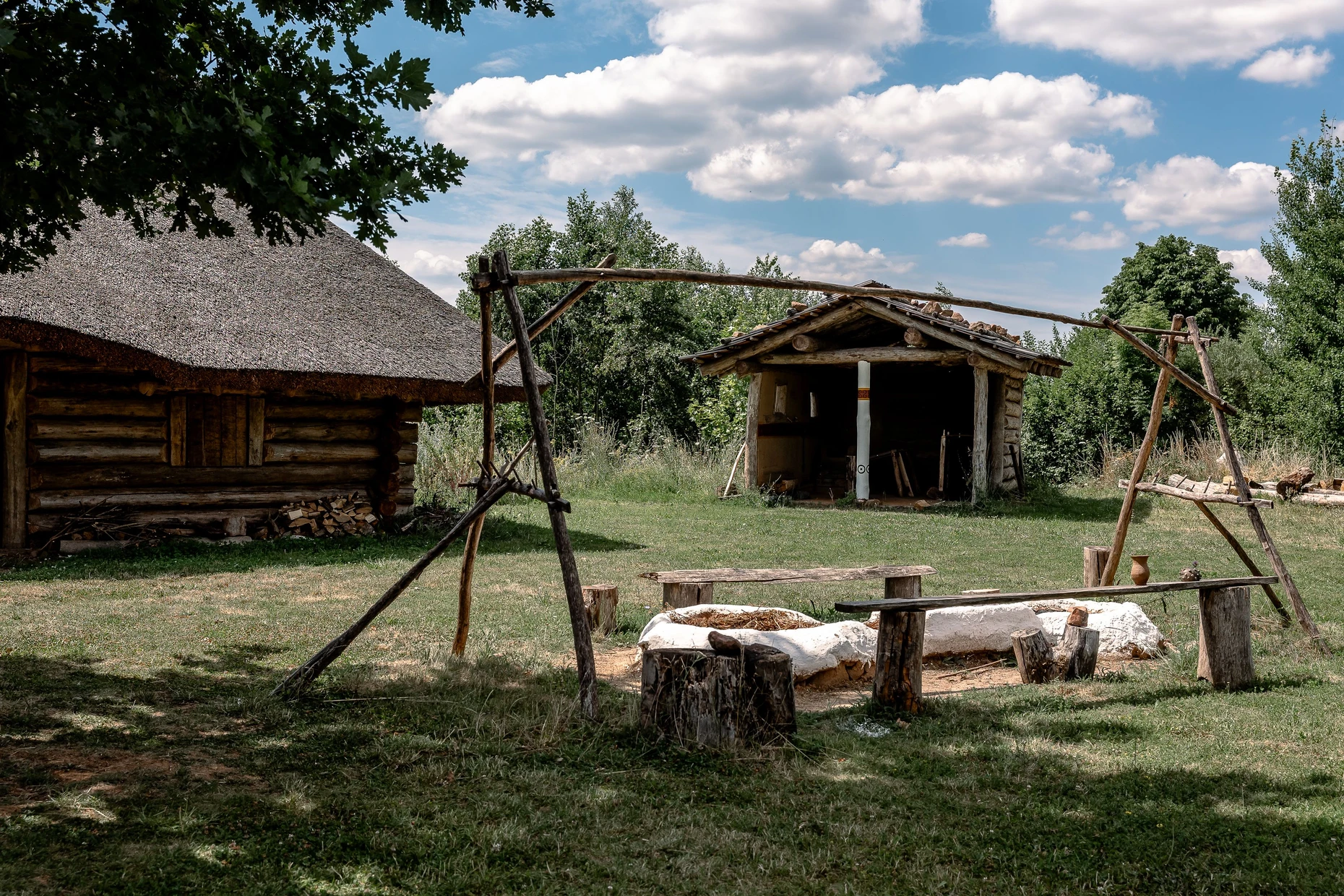 Massiv: Ein Haus im Abschnitt Eisenzeit neben einer Kochstelle mit der Schmiede im Hintergrund