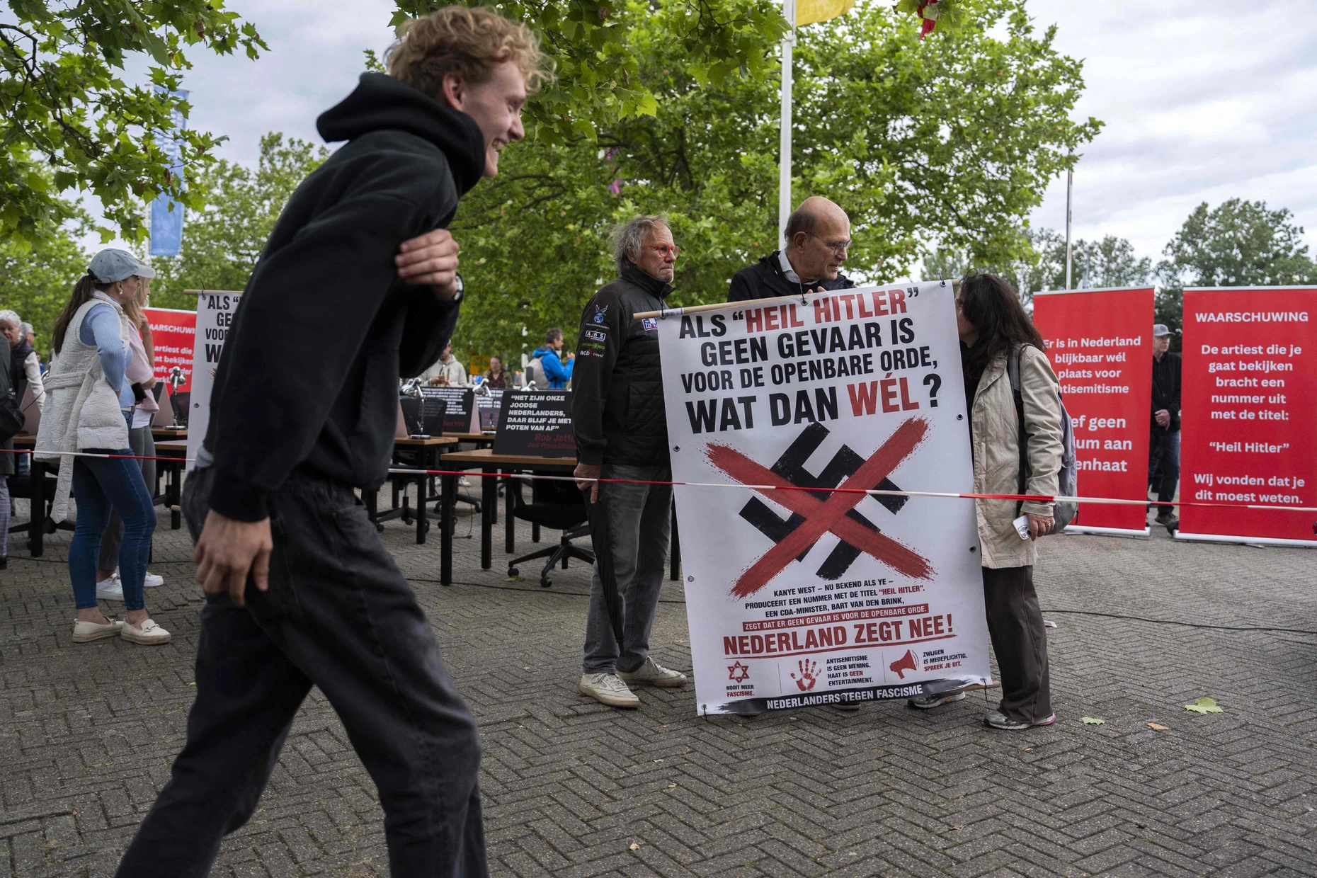 Menschen demonstrieren vor der Konzerthalle mit Plakaten gegen den Auftritt von Kanye West.