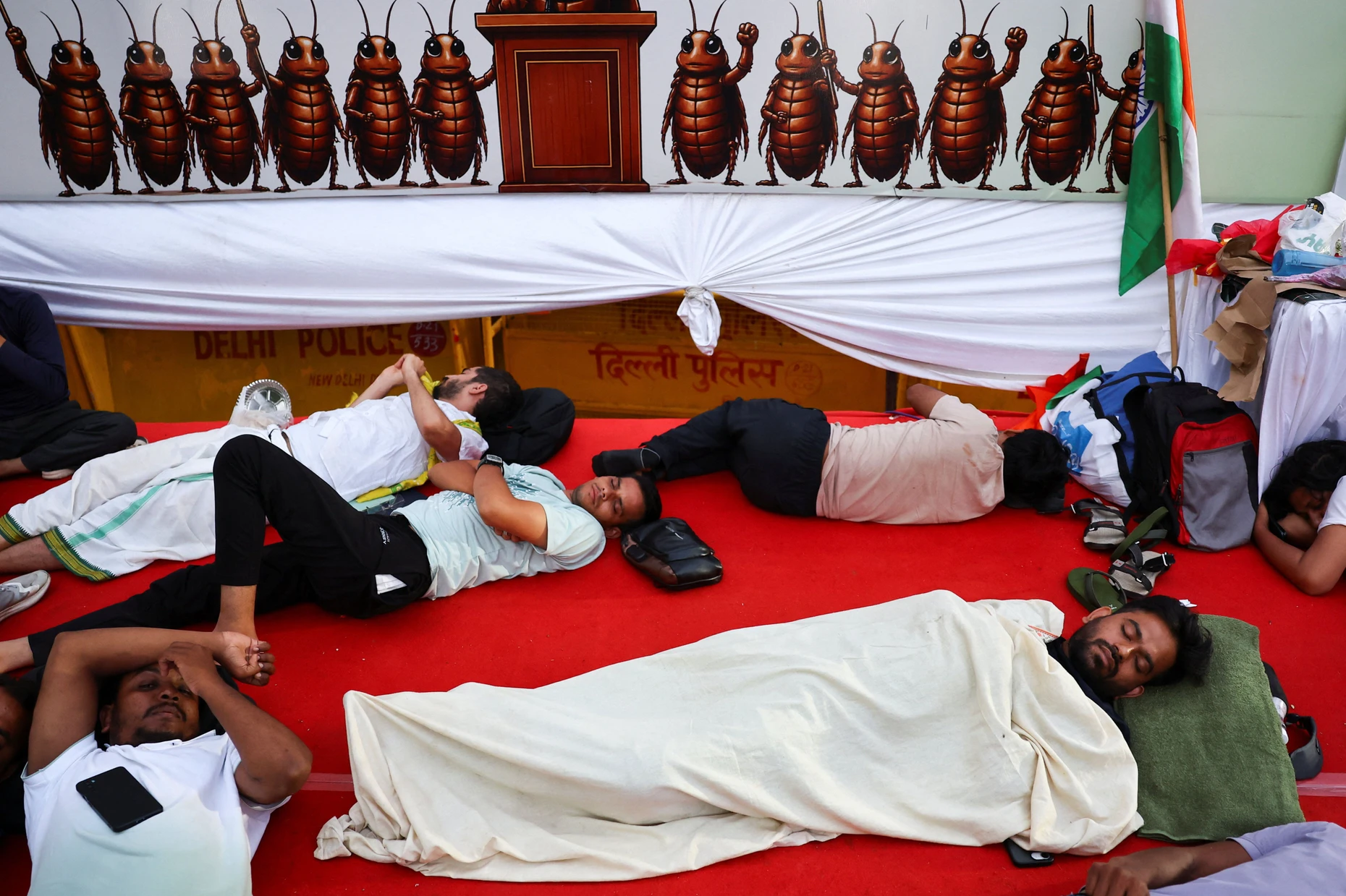 Abhijeet Dipke, head of the Cockroach Janta Party (CJP), sleeps on a stage alongside supporters after spending the night at a protest site during a sit-in protest called by the CJP demanding the resignation of India's Education Minister Dharmendra Pradhan, at Jantar Mantar in New Delhi, India, June 22, 2026. REUTERS/Anushree Fadnavis