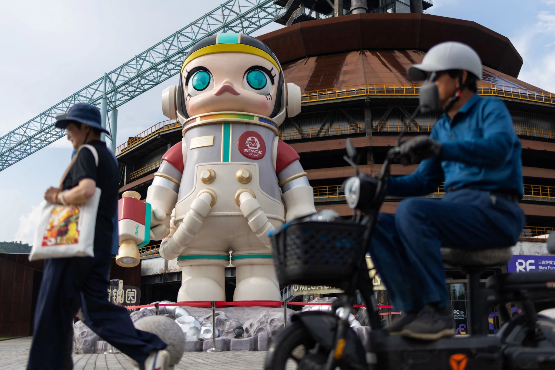 Passanten gehen an der riesigen Figur „Space Molly“ des Spielzeugherstellers Pop Mart im Pekinger Shougang-Park vorbei.