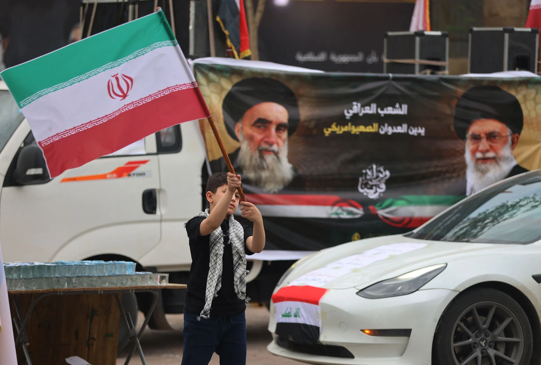 Ein irakischer Junge vor einem Plakat von Ali Khamenei und Ali al-Sistani im April in Bagdad
