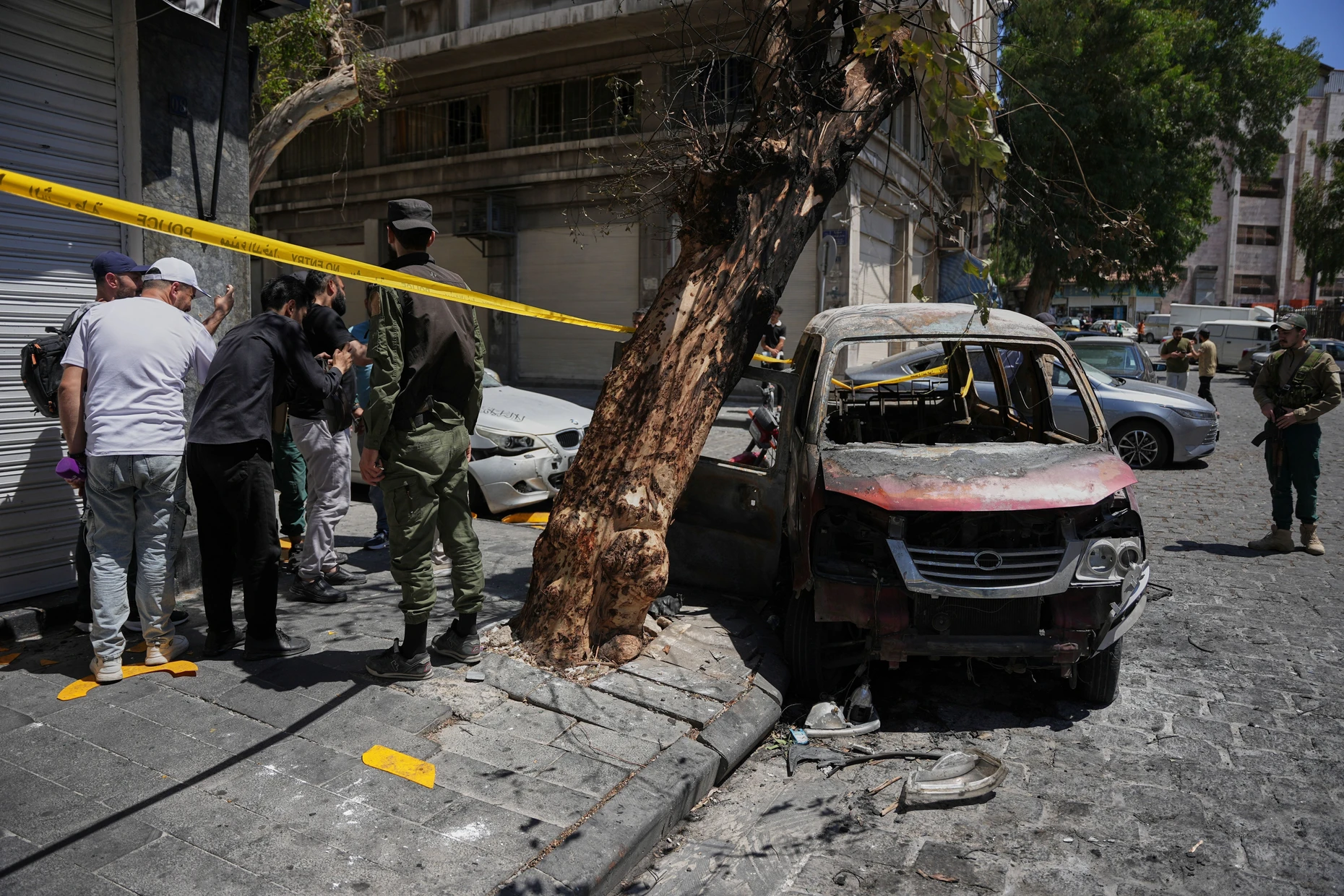 Syrische Sicherheitsleute inspizieren ein verbranntes Fahrzeug nach einem Anschlag in der Nähe des Hotels „Four Seasons“ im Juli 2026.
