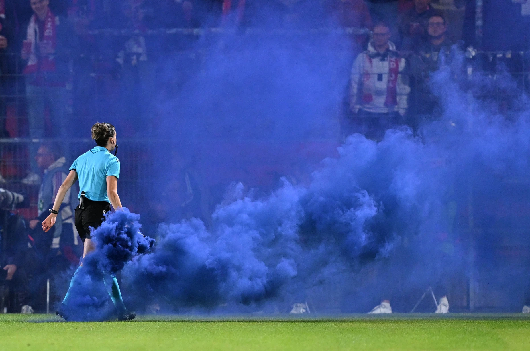 Schiedsrichterin Olatz Rivero Olmedo trägt Pyrotechnik vom Spielfeld.