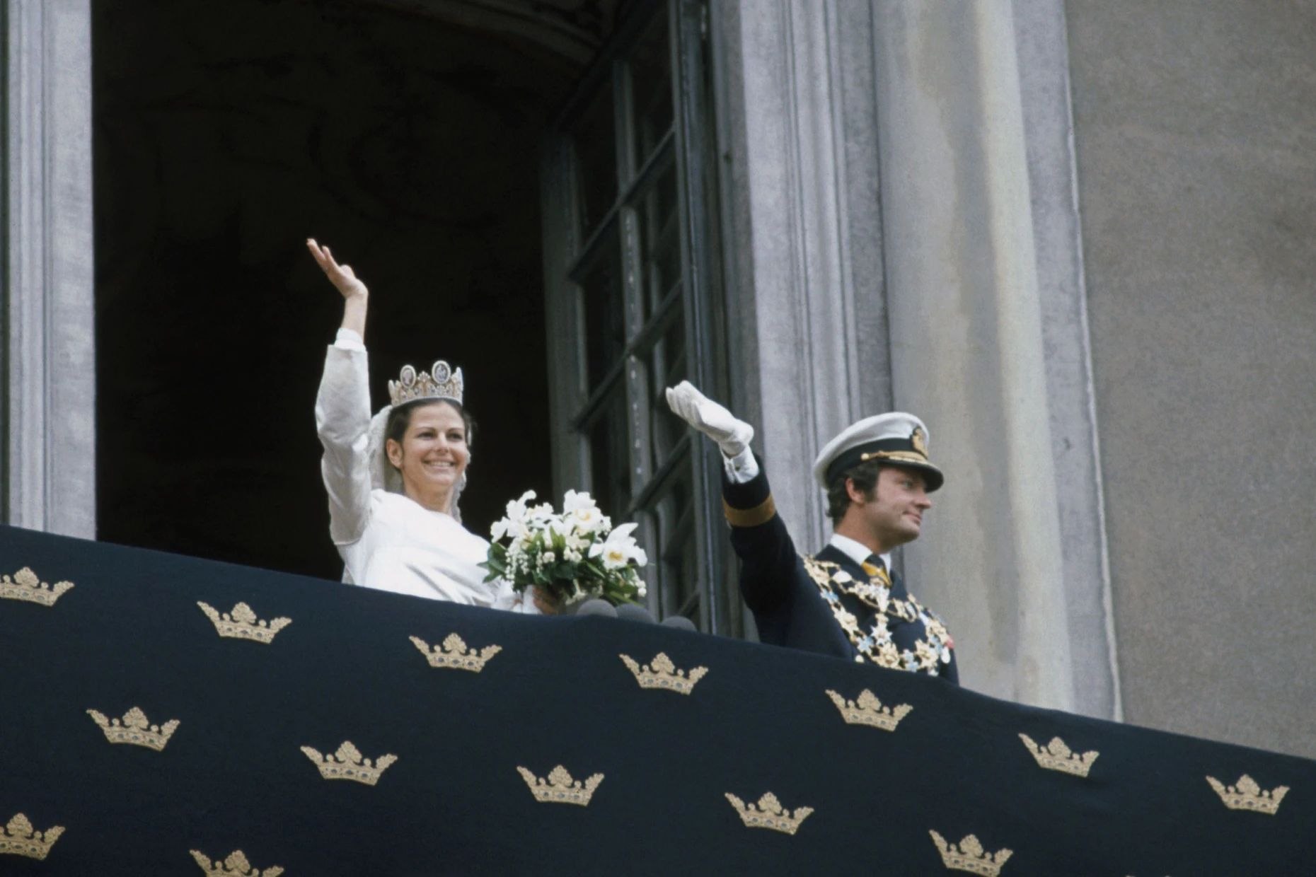 Der erste Auftritt des Paars: König Carl XVI. Gustaf von Schweden und Königin Silvia von Schweden grüßen Zuschauer vom Balkon des Königspalasts nach ihrer Hochzeit.