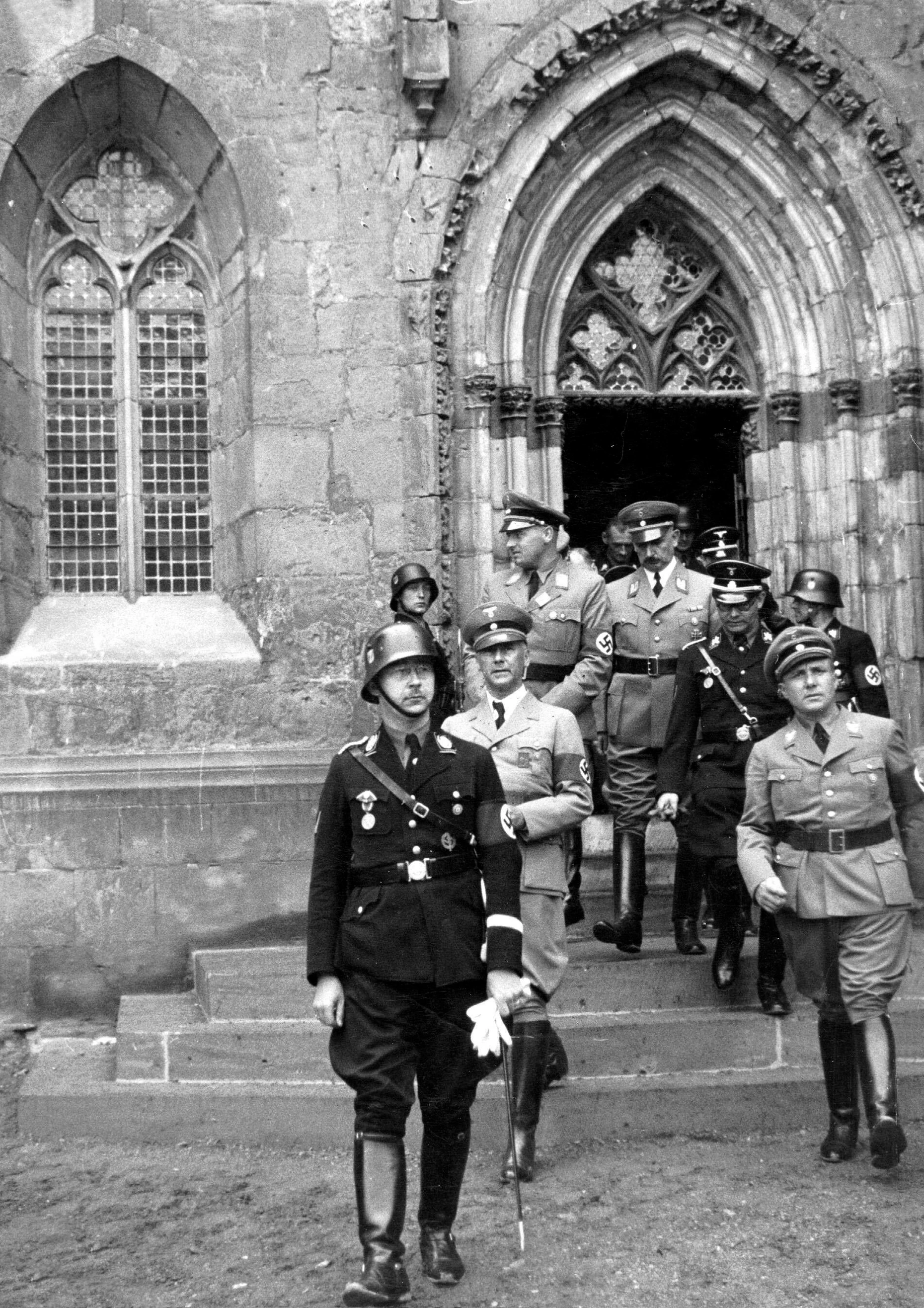 Reichsführer-SS Heinrich Himmler und Reichsleiter Martin Bormann vor dem Eingangsportal des Quedlinburger Domes. Sie wollten ihn zur Wallfahrtsstätte für den deutschen König und Kaiser des Römischen Reiches Heinrich I. (919–936) machen. Das Foto entstand vermutlich auf der Gedenkfeier für König Heinrich I. am 1. Juli 1936.