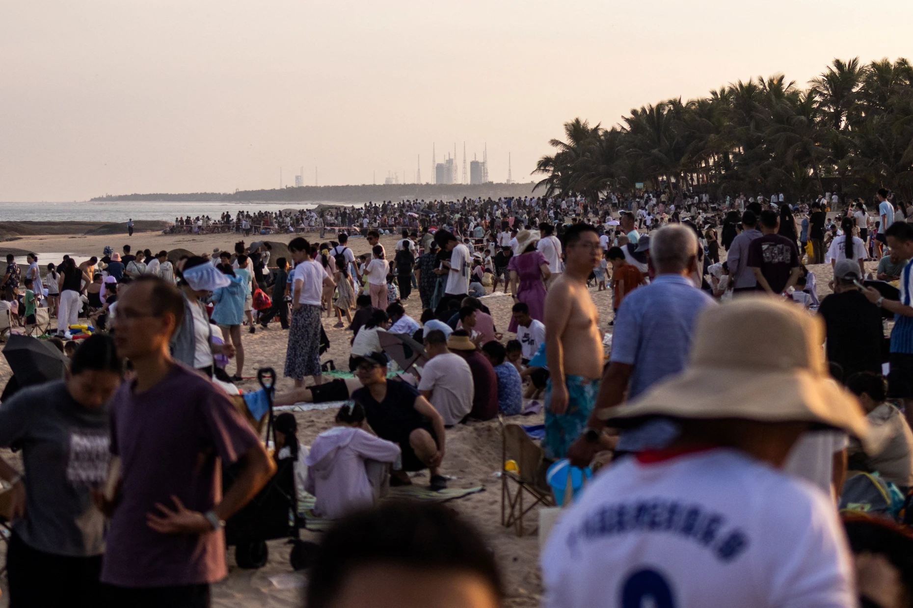 Vom Strand der Qishui-Bucht aus blicken die Zuschauer auf die Startanlagen des Raumfahrtzentrums Wenchang.