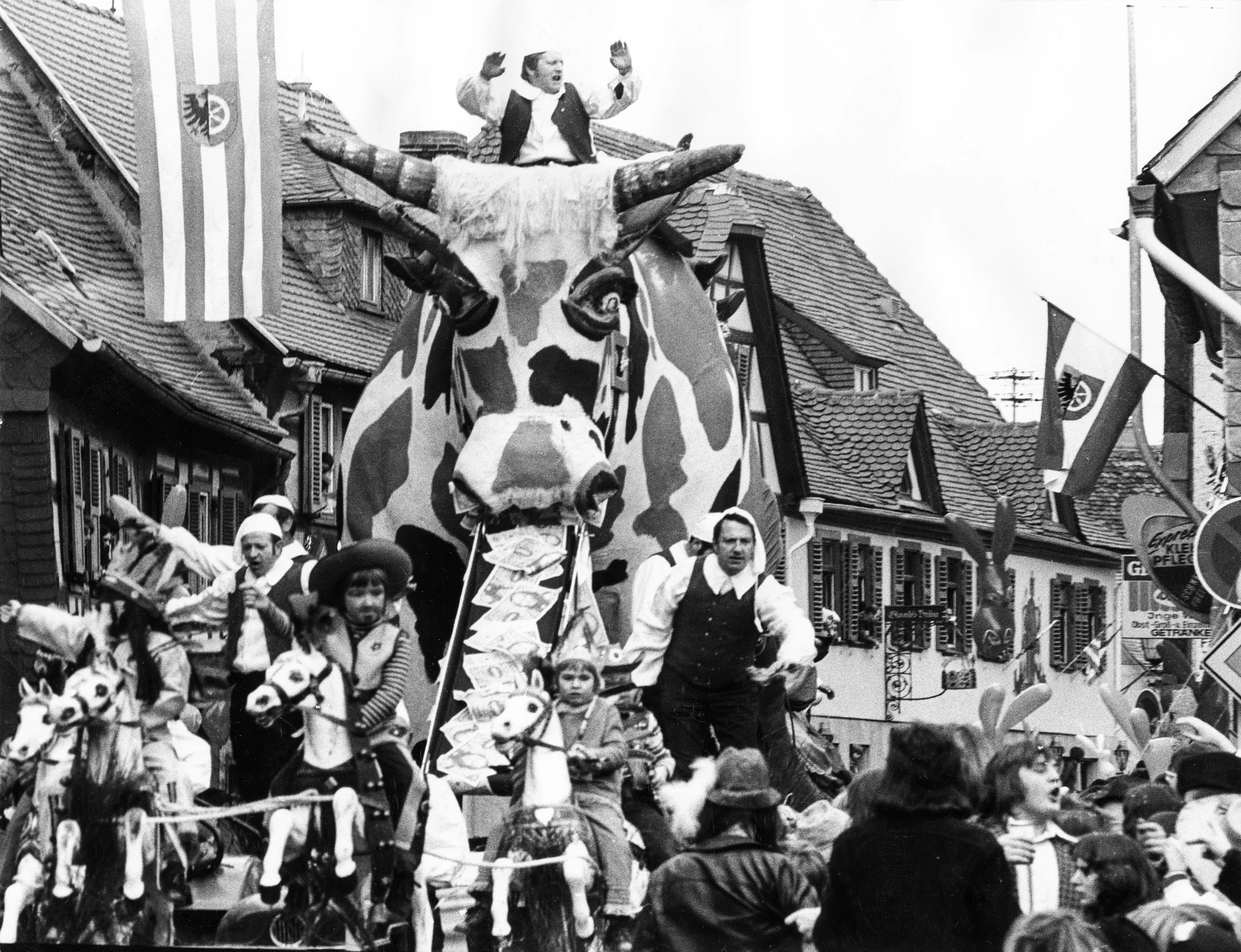 Ein großer Motivwagen fährt am Rosenmontag 1974 durch die historische Altstadt von „Schlumberland“, wie die Einwohner (Schlumber) von Seligenstadt ihre Gemeinde an Fastnacht nennen. Die hessische Kleinstadt an der Grenze zu Bayern führt schon seit Mitte des 19. Jahrhunderts Fastnachtsumzüge durch.