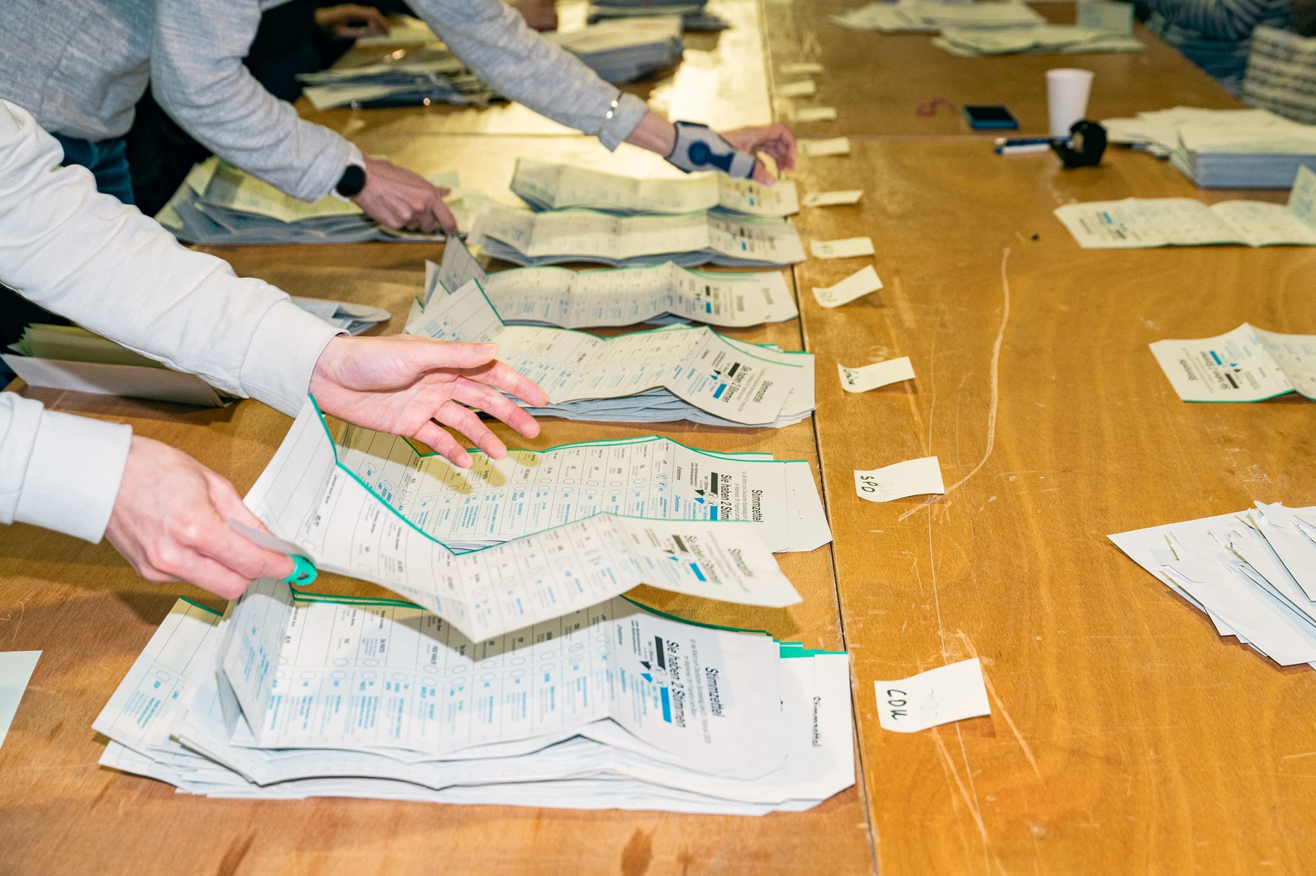 In Frankfurt werden die Briefwahlstimmen zur Bundestagswahl 2025 von Wahlhelfern ausgezählt. Die Wahlhelfer legen die Stimmzettel auf nach Parteien sortierte Stapel.