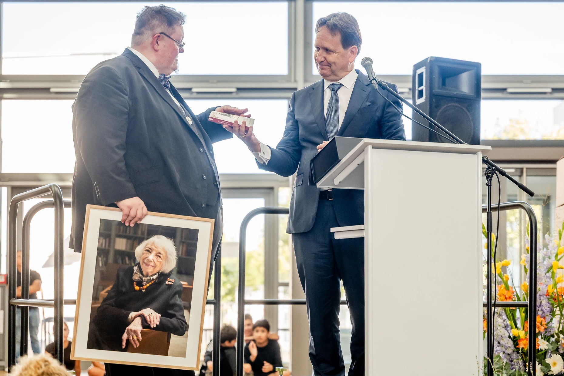 Der Vorstandsvorsitzende der Margot-Friedländer-Stiftung, Karsten Dreinhöfer (rechts), überreicht Schulleiter Nils Franke ein Buch.