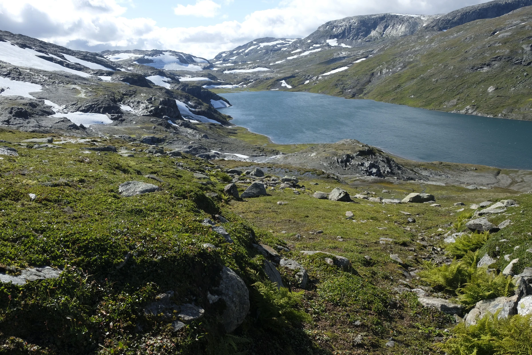 Der See Omnsvatnet liegt zwischen hohen, von Gletschern abgeschmirgelten Bergen.