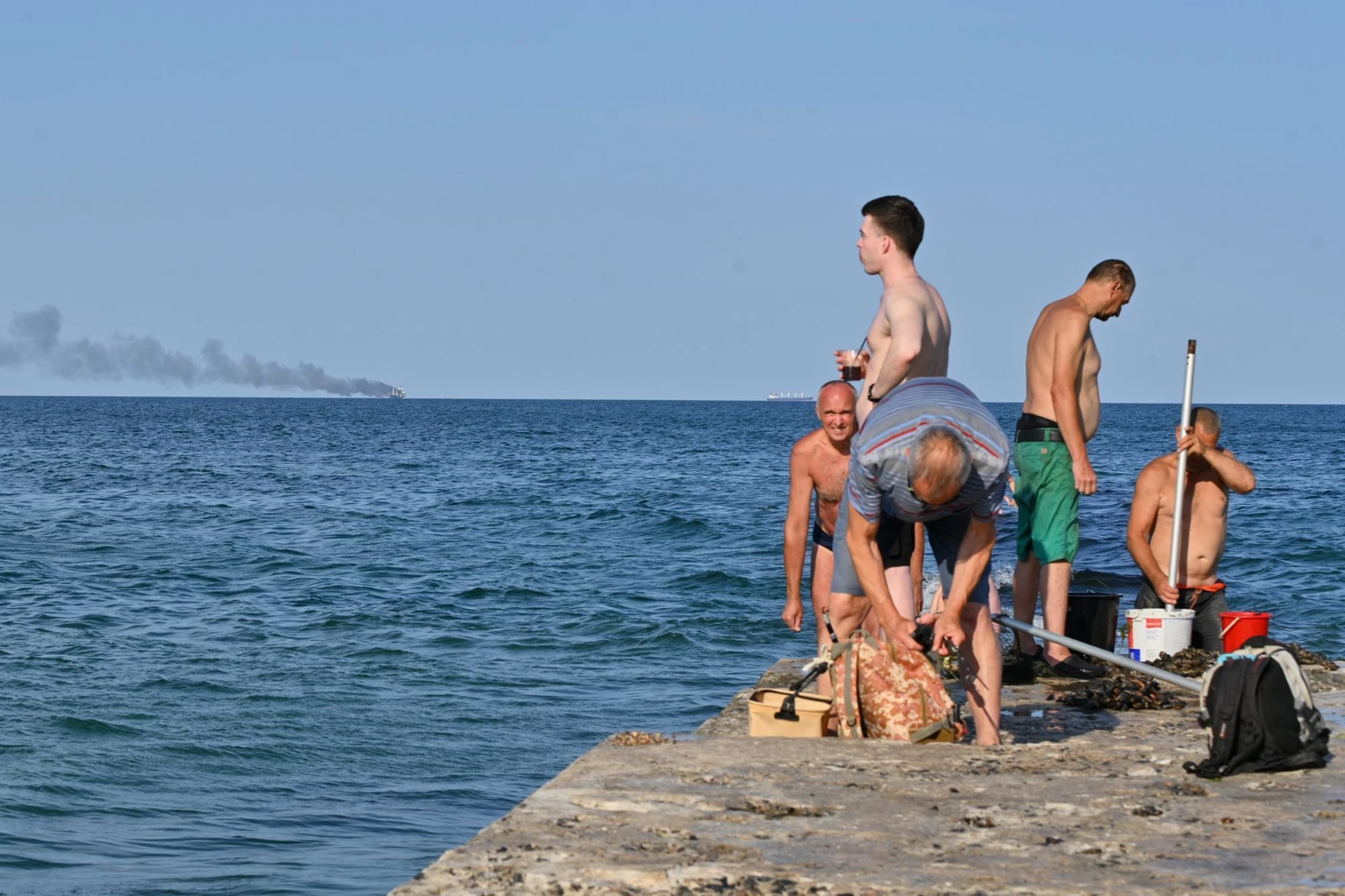 Das Badevergnügen geht weiter: Urlauber an einem Strand in Odessa beachten den brennenden Frachter kaum.