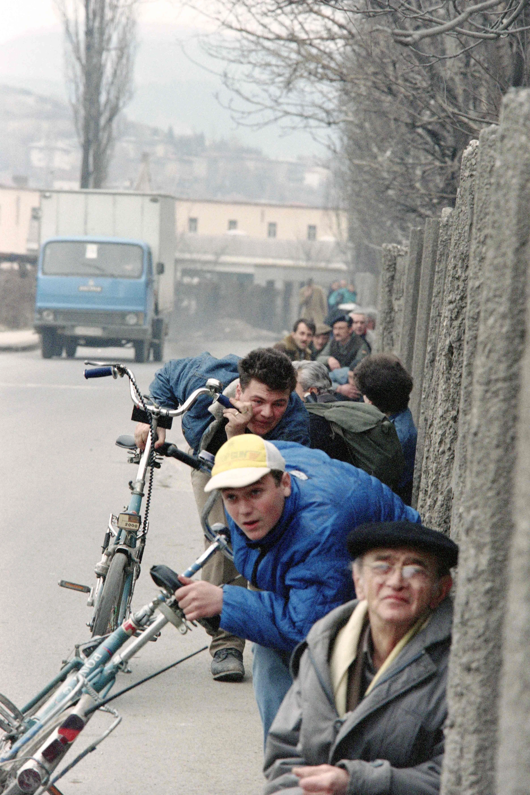 Menschen drücken sich im März 1993 an eine Mauer in Sarajevo, um nicht von Scharfschützen und Granaten getroffen zu werden.