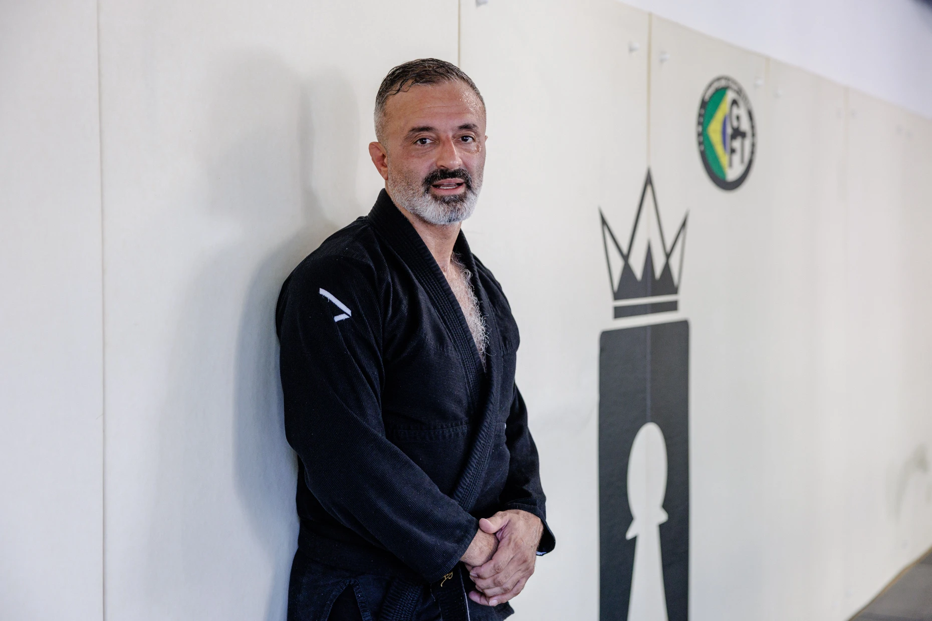 „BJJ ist wie menschliches Schach“: Schwarzgurt Ardalan Gharagozlou (56) neben dem Logo der Kampfsportschule Kingdom.