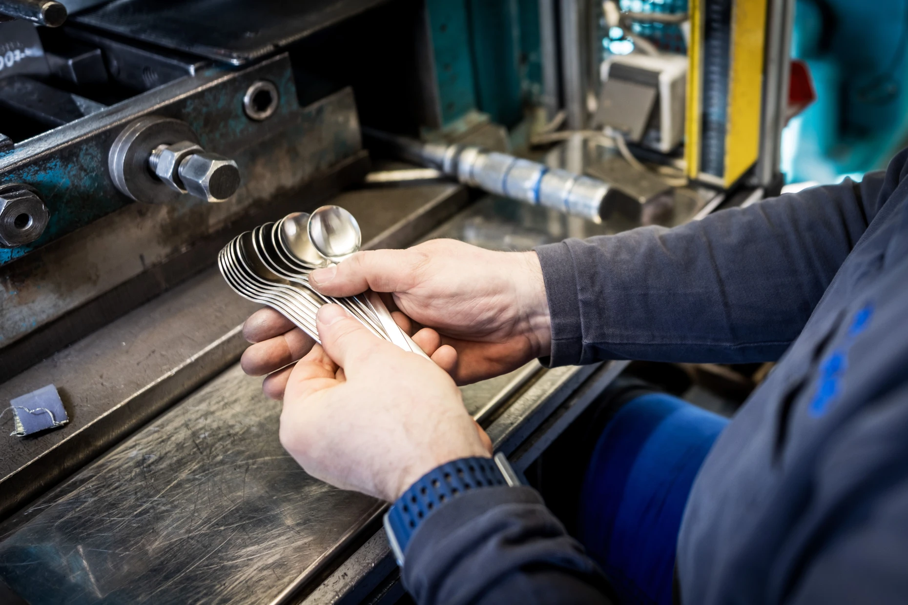 Qualitätskontrolle schon an der Maschine: Ein Mitarbeiter kontroliert die Produktion von Löffeln.