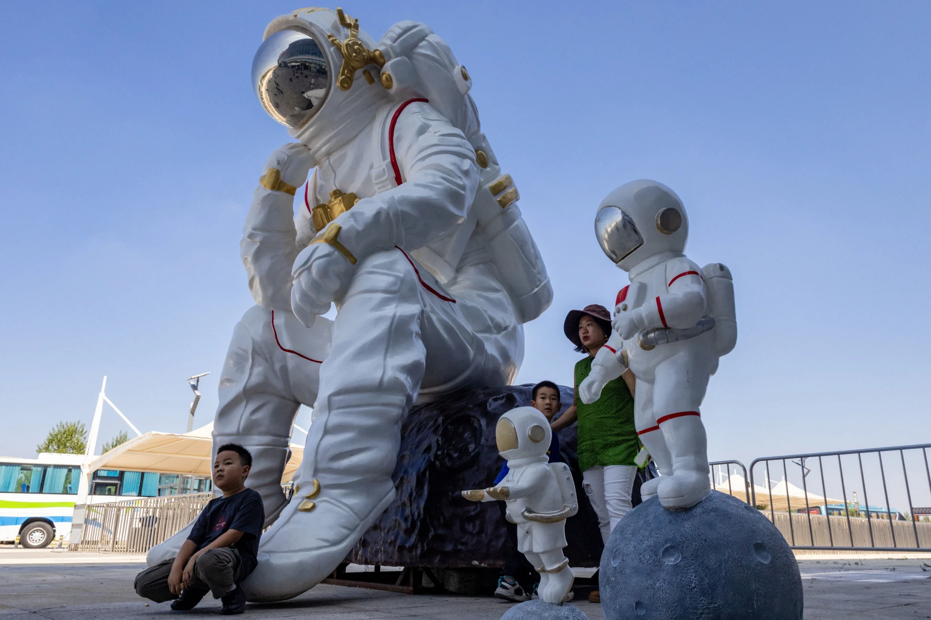 Eine Frau posiert mit ihren zwei Kindern neben einer überlebensgroßen Astronautenfigur am Besucherzentrum.