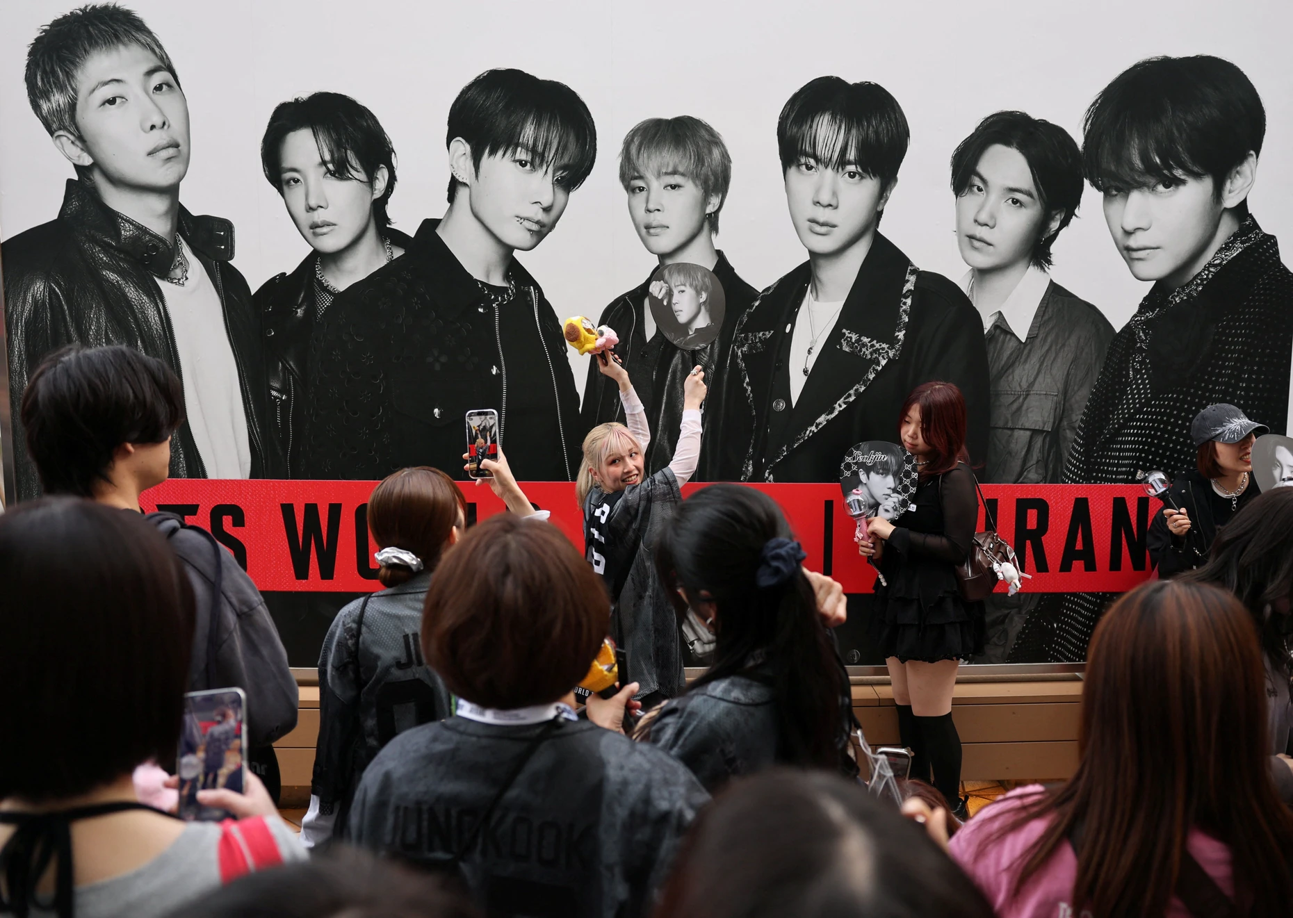 Mitglieder der BTS Army posieren vor einem Plakat der Boygroup bei einem Konzert der „Arirang“-Welttournee in Tokio.