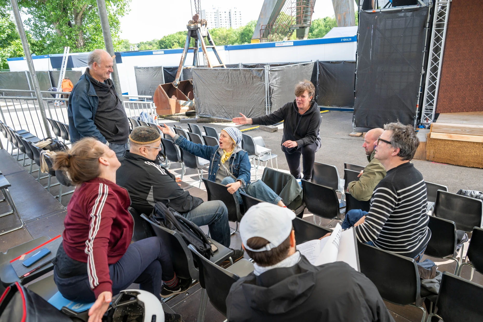 Regisseurin Sarah Groß (schwarzes Hoodie) bei der Probe des Ensembles am Spielort „Barock am Main“ in Frankfurt-Griesheim.