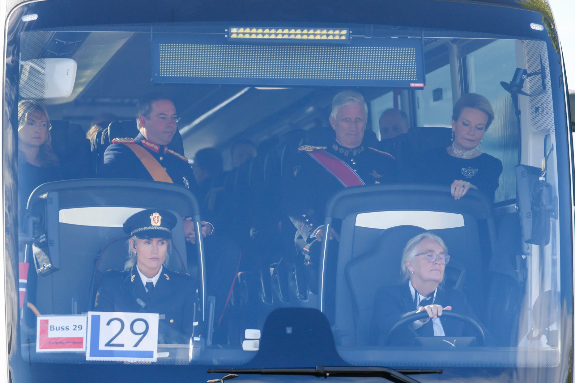 Werden am Flughafen abgeholft: Der belgische König Philippe und Königin Mathilde (r) sitzen in einem Bus am Flughafen Oslo bei ihrer Ankunft zur Beisetzung von König Harald V.