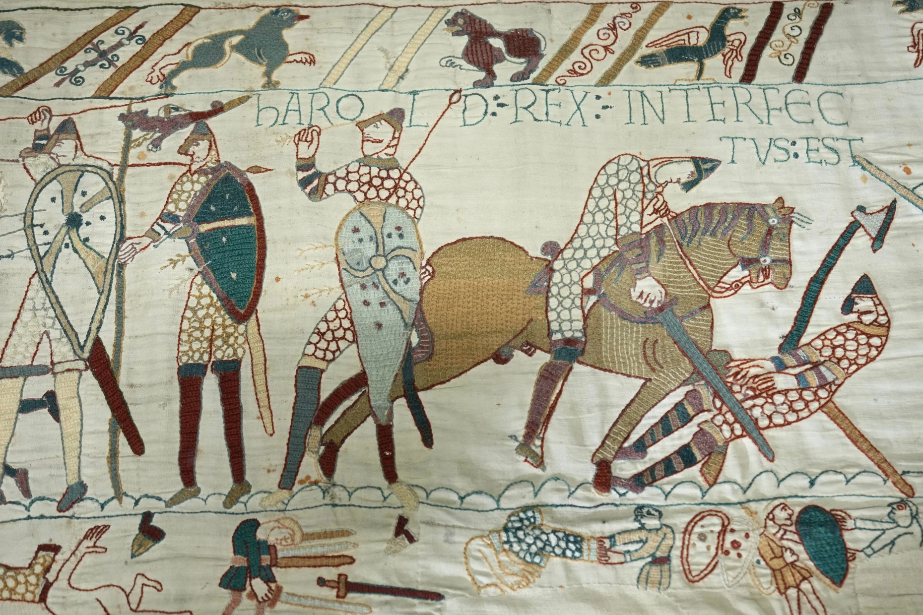 Grauen des Kriegs II: Während in der Mitte des Teppichs von Bayeux König Harold getötet wird und seine Truppen fliehen, ziehen in der unteren Bordüre Leichenfledderer den toten Kriegern die kostbaren Kettenhemden aus.