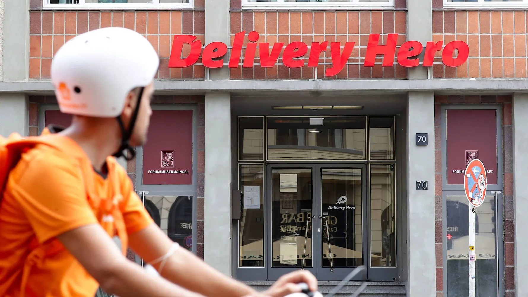 Merkwürdige Normalität in Berlin: Ein Lieferando-Fahrer fährt am Hauptsitz von Delivery Hero in der Oranienburger Straße vorbei. Der deutsche Konzern hat in Deutschland kein Geschäft mehr.