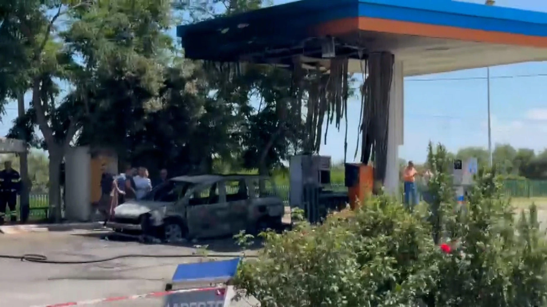 People view the burnt car at the gas station in Amendolara after the fire was extinguished.