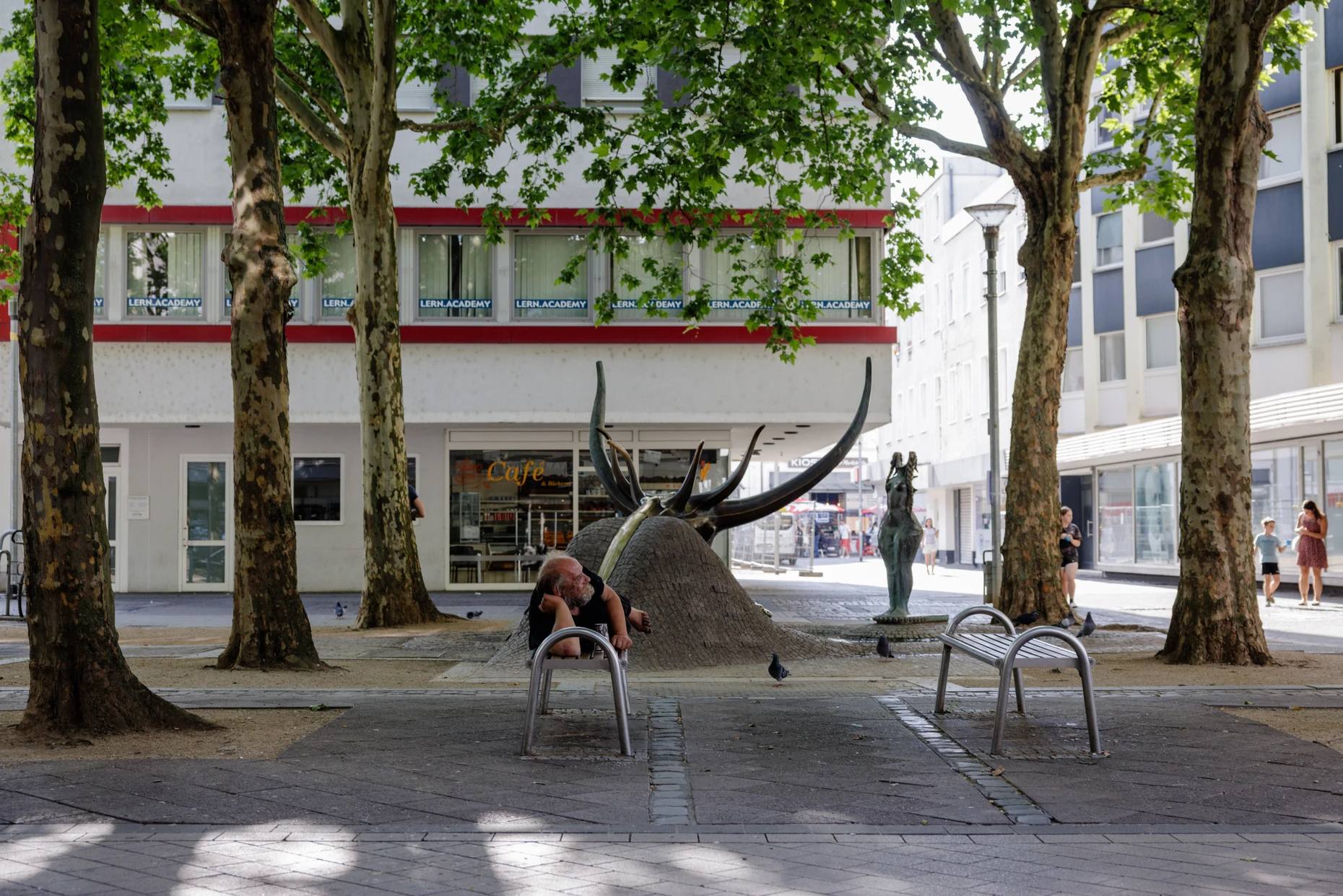 Zentral: Auf dem Europaplatz liegt ein Obdachloser im Schatten der Bäume.