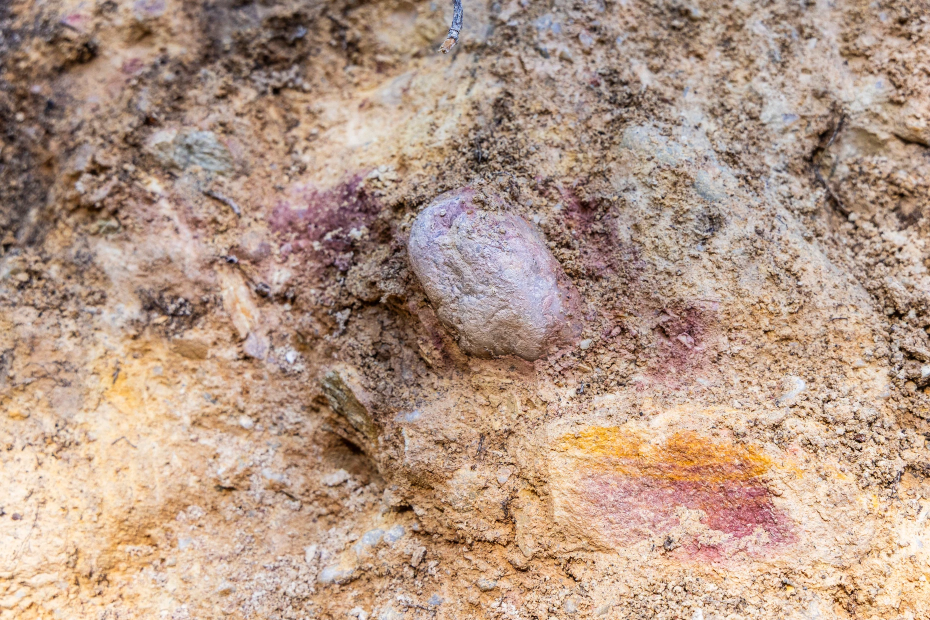 Schwarze und rote Spuren im Sediment weisen auf Holzkohle und Mainsandstein hin.