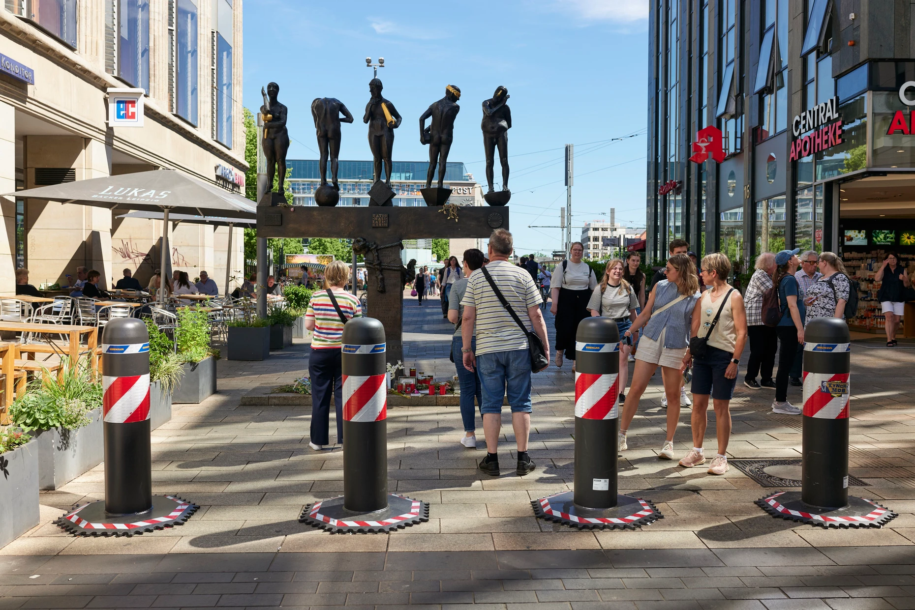 Seit der Amokfahrt am 4. Mai stehen Poller in der Grimmaischen Straße in Leipzig. Am Fuß der Bronzeplastik liegen Blumen für die Opfer des Anschlags.