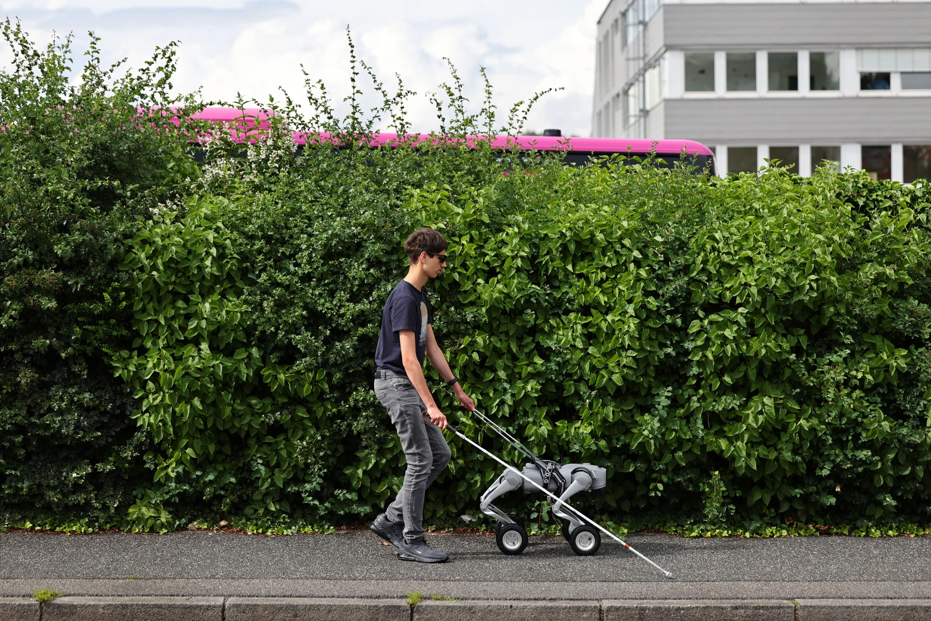 Julian Schiering, der blind geboren wurde, geht mit einem Unitree Go2-W Roboterhund, der von Florian Weichselbaumer, dem CEO von Labland.ai, gesteuert wird.