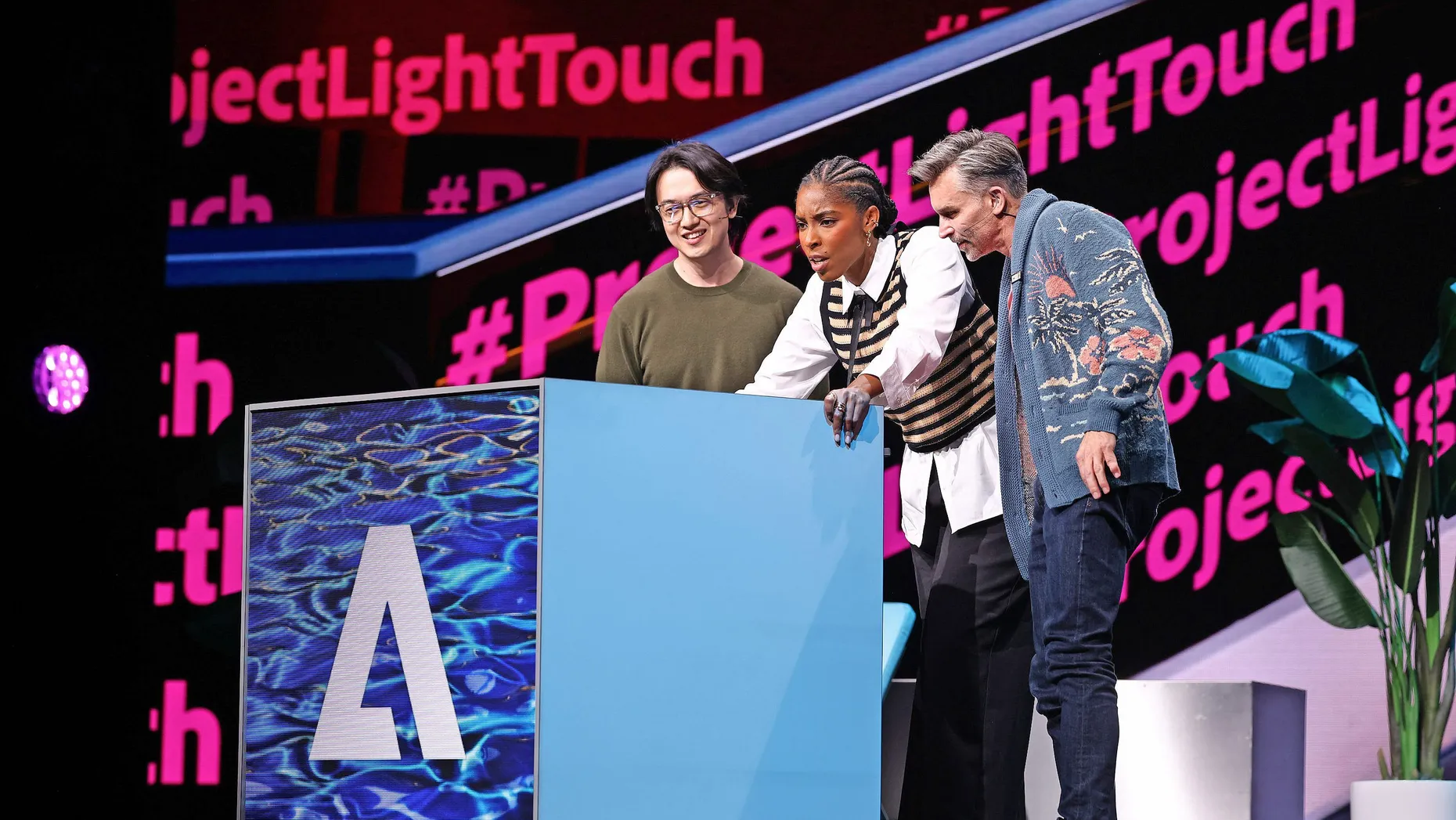 Adobe blickt zuversichtlich auf das Geschäftsjahr: Zwei Mitarbeiter präsentieren gemeinsam mit Schauspielerin Jessica Williams neue Adobe-Software