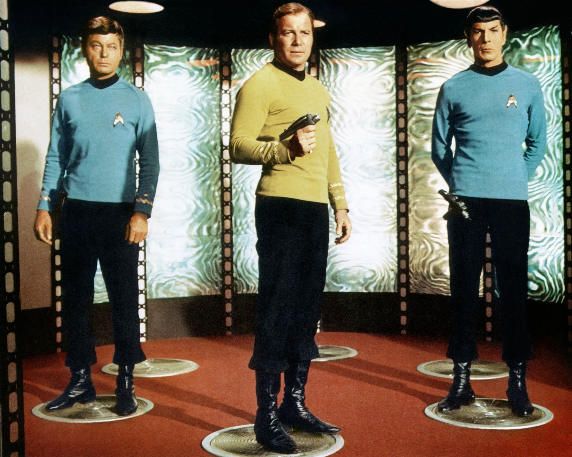 „Mr. Scott, three to beam up“, wird Captain James T. Kirk (William Shatner, M.) gesagt haben. Dr. „Pille“ McCoy (DeForest Kelley, l.) und Mr. Spock (Leonard Nimoy) sind mit von der Partie.
