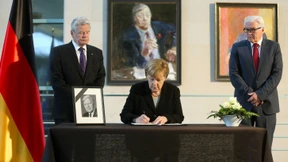 Kondolenzbücher und Blumen am Jägerzaun